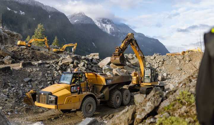 Close-up view of a Cat excavator loading a Cat 740B with large boulders following the 2021 BC Floods.